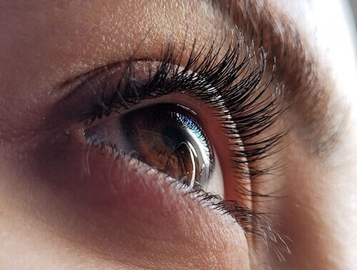 Close-up de olho humano com cílios longos e detalhes da íris, destacando a beleza natural dos olhos. Ideal para conteúdo sobre saúde ocular e beleza.
