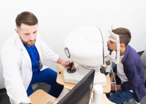 Médico realiza exame de vista com equipamento oftalmológico em jovem paciente em consultório
