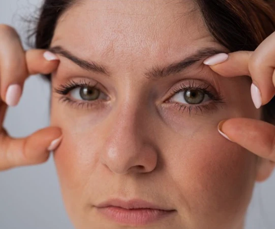 Mulher ajustando a pele ao redor dos olhos, destacando a importância dos cuidados faciais para a aparência. Dicas de beleza para um olhar mais jovem.